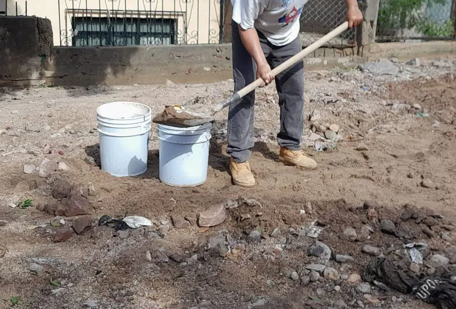 Persona quitando el lodo de la calle con una pala y cubetas