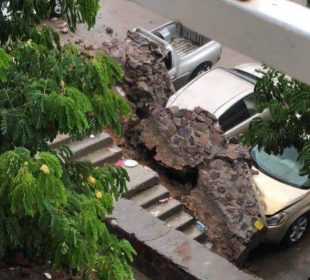 Pared caída sobre cofres de autos