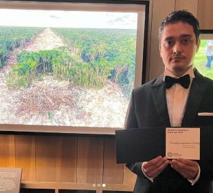 Fernando Constantino Martínez Belmar junto a fotografía de la deforestación del Tren Maya