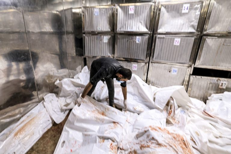 Hombre cubriendo cuerpos en morgue de Gaza