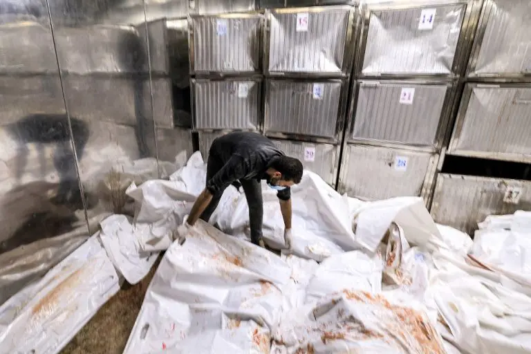 Hombre cubriendo cuerpos en morgue de Gaza