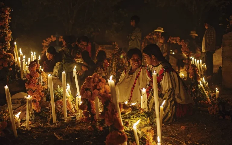 Mujeres sentadas rodeadas de velas y cempasúchil