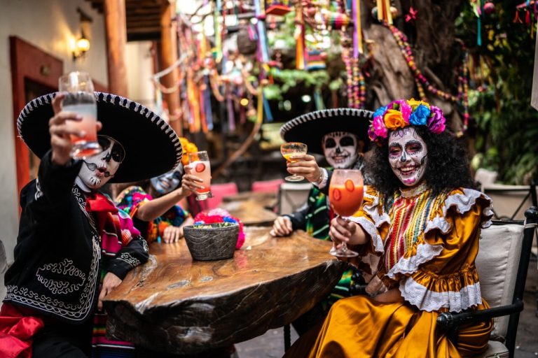 Personas vestidas de catrina sosteniendo bebidas