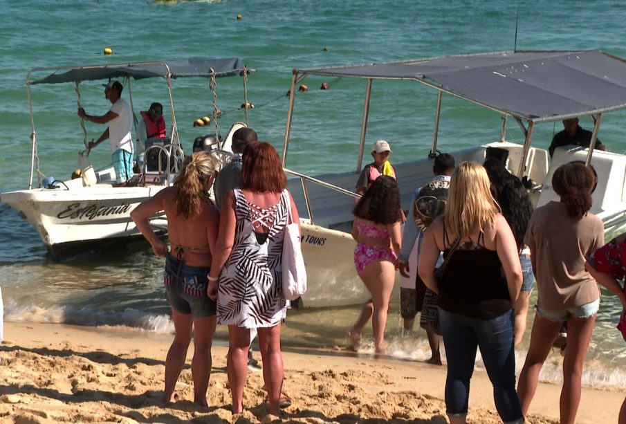 Turistas y embarcaciones en playa