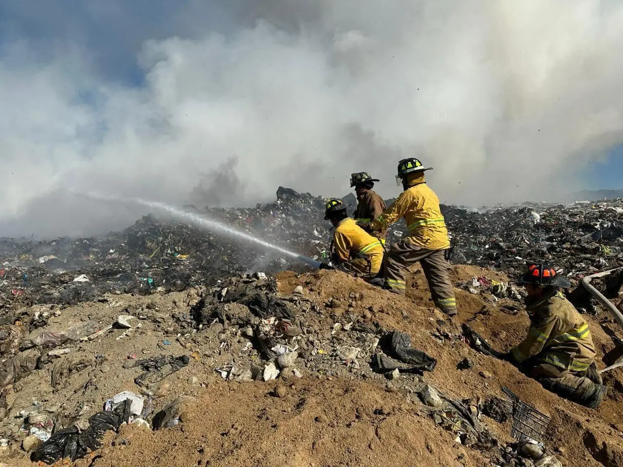 Bomberos sofocando incendio en relleno sanitario