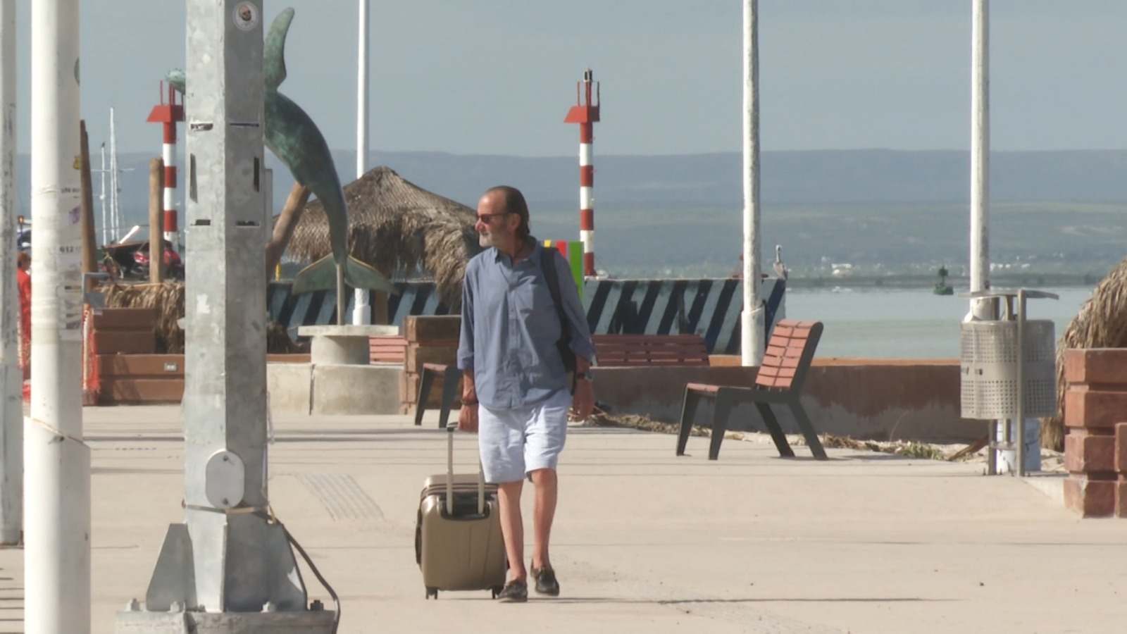 Turista caminando con su maleta en malecón de La Paz