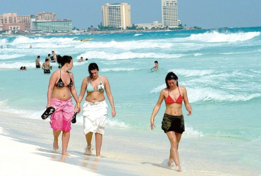 Tres turistas paseando por la playa