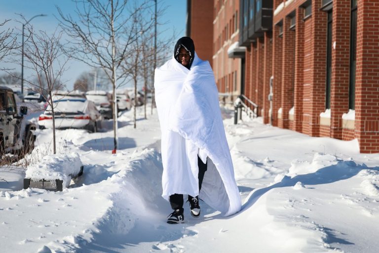 Hombre caminando con manta sobre la nieve