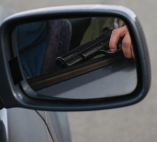 Hombre viajando en auto con pistola en mano