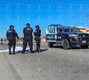 Policías resguardando cuerpo cubierto con sabana