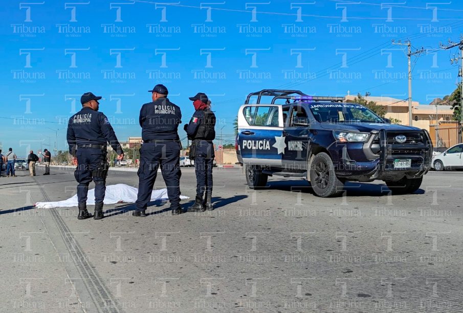 Policías resguardando cuerpo cubierto con sabana