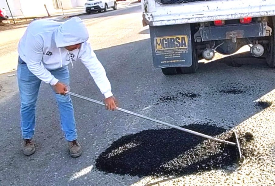 Obrero tapa bache con asfalto