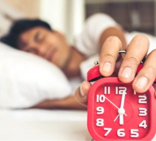 Hombre despertando y apagando el reloj