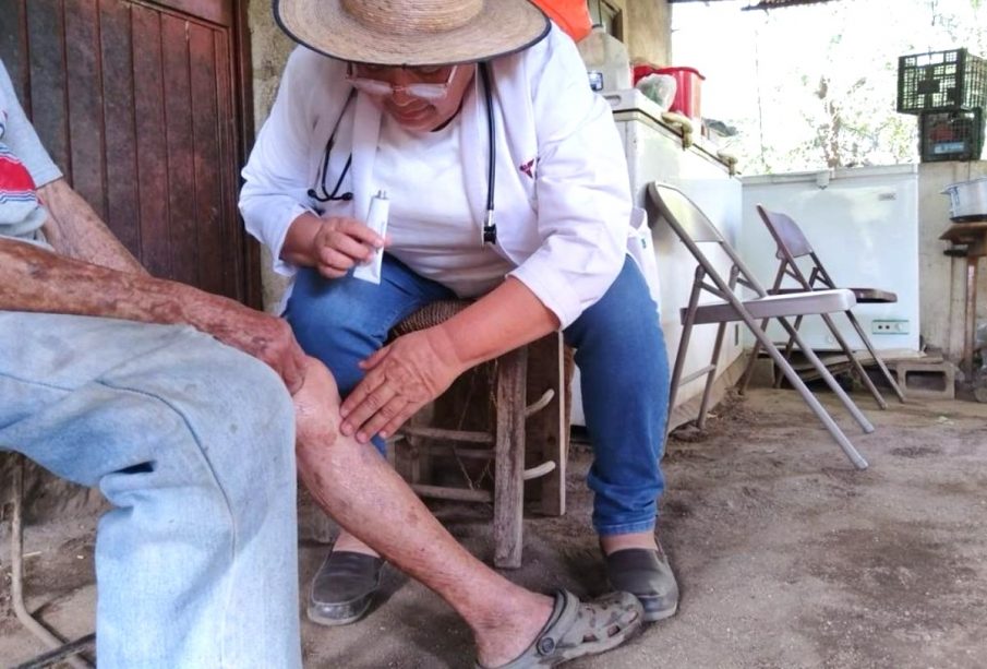 Doctora unta crema a pierna de adulto mayor