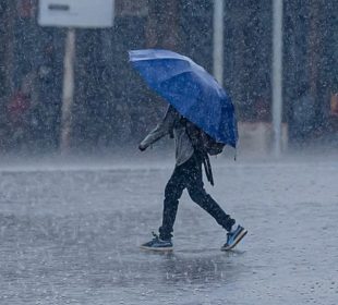 Hombre caminando con paraguas bajo lluvia