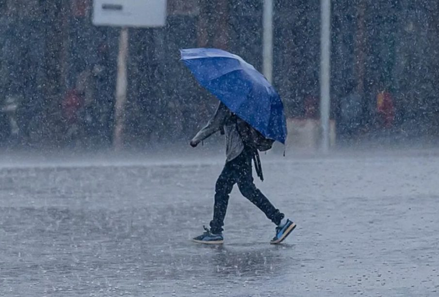 Hombre caminando con paraguas bajo lluvia