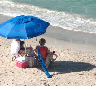 Mujeres turistas bajo una sobrilla en la playa
