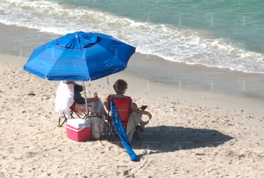 Mujeres turistas bajo una sobrilla en la playa