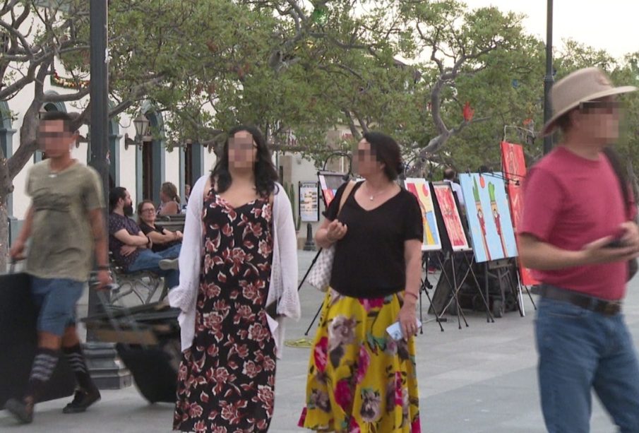 Personas caminando en plaza con rostros ocultos