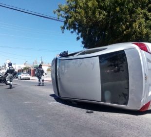 Vehículo plateado volcado en la carretera