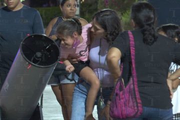 Niña y su mamá viendo el cielo en un telescopio