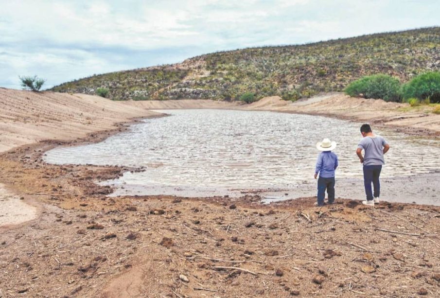 Río con agua corriendo y dos granjeros observan correr el agua