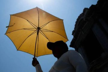 Mujer cubriendose del sol con sombrilla