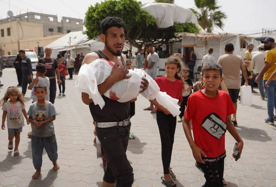 Palestino cargando a infante muerto tras ataque de Israel a Rafh