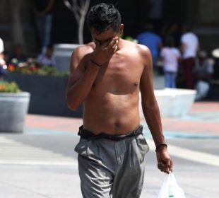 Persona sin playera con calor camina por la calle