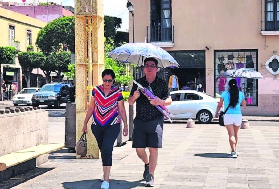 Personas se cubren del calor con un paraguas