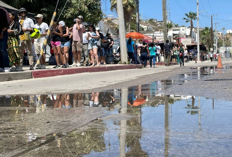 Aguas negras en calle donde turistas hacen fila para votar