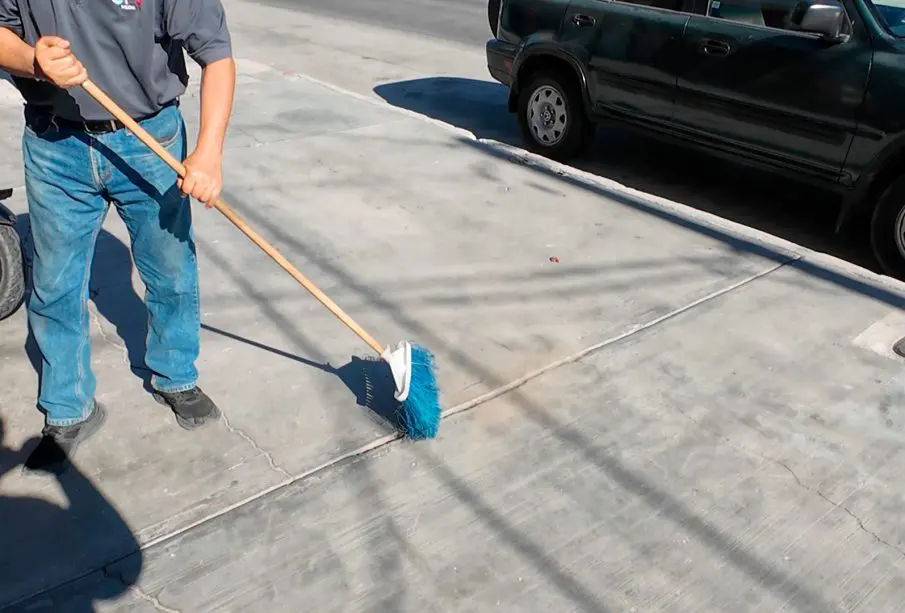 Persona barriendo una banqueta