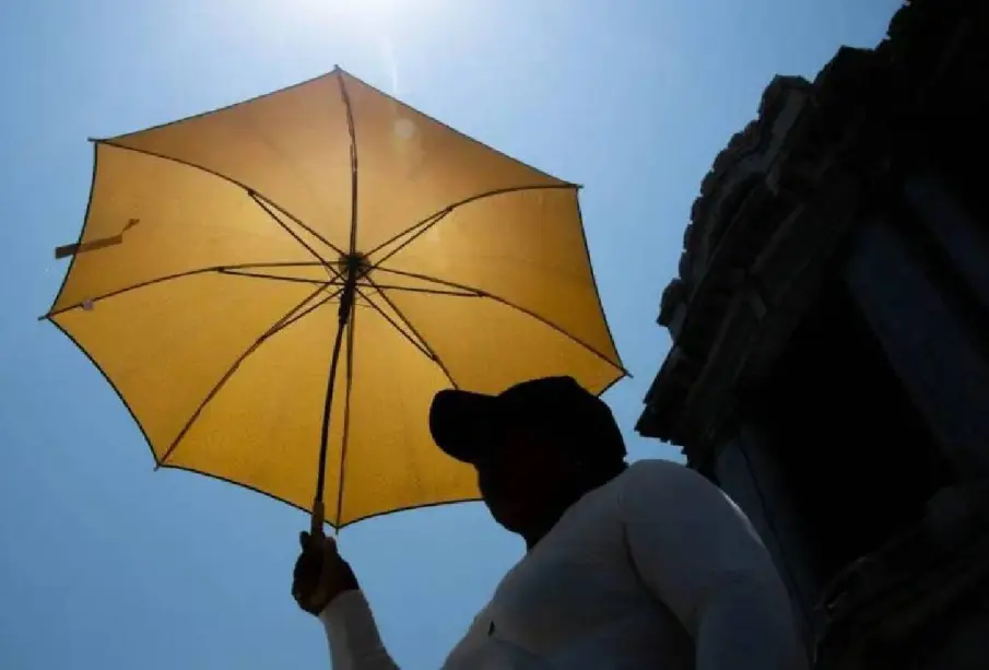 Persona se tapa con una sombrilla por el calor