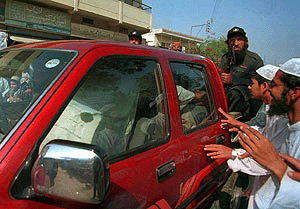 Religious students watch the van carrying Maulana Masood Azhar, freed in a deal in the Indian Airlines plane hijack last week, being escorted back after a Press conference in Karachi on Thursday.