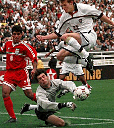 United States forward Brain McBride (20) jumps over Iran goalkeeper Hadi Tabatabei (centre) after a save while defender Satar Hamedani looks on during the first half on Sunday at the Rose Bowl in Pasadena, Calif. The game ended in a 1-1 tie.