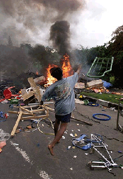  A Muslim rioter throws goods from a Christian Chinese-owned shop into a bonfire in Mataram on the resort island of Lombok, about 2,600 kilometers (1,600 miles) east of Jakarta on Wednesday. Rioters continued to rampage on the tourist island targetting mainly Christian shops and homes in retribution for sectarian violence which has spread from Indonesia's Spice Islands
