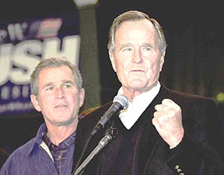 Republican Presidential candidate George W. Bush listens as his father, former President George Bush, speaks on his behalf during campaigning in Milford, New Hampshire, on Saturday