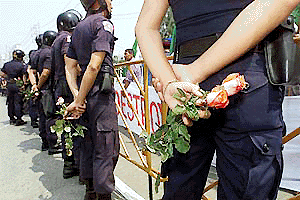 Thai riot police stand in front of protesters outside the United Nations Conference on Trade and Development, in Bangkok on Monday. Protesters in a show of non-violence passed out St. Valentines Day roses to police.