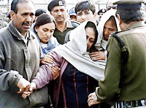The widow of J.S. Pathania, Assistant Commandant of the Border Security Force, (C) falls unconscious as the remains of her husband are carried out of a plane from Srinagar, 15 February 2000. Pathania, who was killed in a daring raid by Muslim separatist militants near Srinagar, managed to kill two militants, one of which was later identified as top Lashkar-e-Toiba leader Irfan Ahmad, before succumbing to his wounds.  AFP photo
