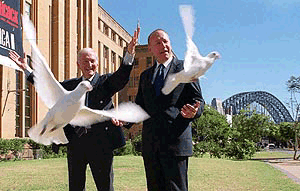 Author Bryce Courtney (left) of Australia and New South Wales shadow Olympics minister Chris Hartcher release 14 white peace birds in hope that the Sydney Organizing Committee for the Olympic Games Board will endorse 30 seconds of silence at Opening Ceremony of the Sydney Olympic Games. In the background is the Sydney Harbour Bridge