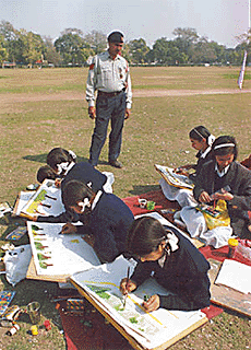 A traffic policeman keeps an eye on participants during a painting competition organised by the police for schoolchildren in New Delhi