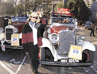 A cheering participant stands in front of a vehicle at the Vintage and Classic Car Rally in New Delhi on Sunday