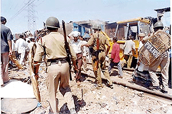 Police personnel clear unauthorised hutment along the Central Railway track at Govandi. The demolition drive is a part of the maintenance work being undertaken by the Railways.  PTI photo
