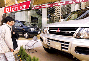 Customers examine a new model of Mitsubishi Motors' sports utility vehicle Pajero at a showroom of the company's headquaters in central Tokyo 07 March 2000. DaimlerChrysler AG and Mitsubishi Motors are negotiating a comprehensive alliance which would give the US-German giant a long-sought stake in a Japanese automaker.    (ELECTRONIC IMAGE)   AFP PHOTO/Toru YAMANAKA