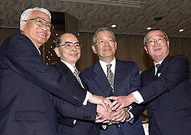 Four presidents of Japanese banks, from left, Tomoaki Hirano, of Nippon Trust Bank, Satoru Kishi, of Tokyo-Mitsubishi Bank, Akio Utsumi, of Mitsubishi Trust and Banking, and Hiroshi Hayashi, of Tokyo Trust Bank, put their hands together after announcing their plan to integrate their operation to set up a holding company, Mitsubishi Tokyo Financial Group Inc. in Tokyo Wednesday. 