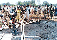 Police officials, assisted by forensic experts, attempt to extricate shoes and other material of the victim whose body was found earlier in a coal tar dump in Hallo Majra on Sunday.  Tribune photo by Parvesh Chauhan