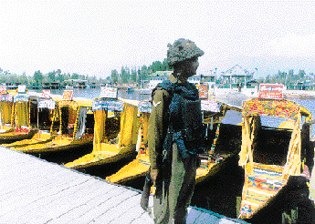 Empty "shikaras" lined up on Dal Lake as a jawan keeps guard