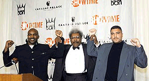 Evander Holyfield (left) and John Ruiz (right) raise arms with boxing promoter Don King during their news conference at Caesars Palace Hotel in Las Vegas on Thursday