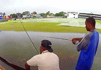 Andrew Salomon, right, and Kudyard Ceres, attempt to catch some fish at the flooded Bourda cricket grounds in Georgetown, Guyana