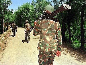 Indian soliders walk along a road on the way to Dooru village, 70 km south of Srinagar on Tuesday. The Indian security forces have launched a manhunt for suspected Muslim militants who detonated a powerful landmine in this village on Monday, killing Kashmir's Power Minister Ghulam Hasan and four others. �  AFP photo